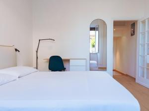 a bedroom with a large white bed and a green chair at Casa Acquachiara - a due passi dalla spiaggia in Monte Argentario