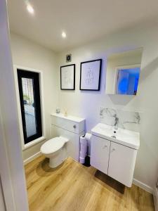 a white bathroom with a toilet and a sink at Peaceful retreat with hot tub and sauna in Edgware