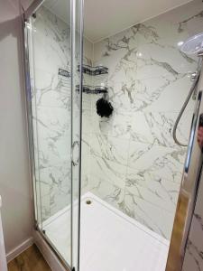 a bathroom with a shower with a marble wall at Peaceful retreat with hot tub and sauna in Edgware