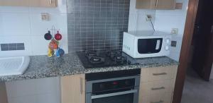 a kitchen with a microwave and a stove top oven at Charming and Cosy Apartment close to TUNISIA MALL Lac2 Tunis in Tunis