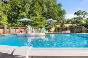 a swimming pool with chairs and umbrellas at The Gardenia House in Charleston