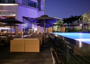 a pool with tables and umbrellas next to a building at Sathorn Prime Residence & Rooftop Sky Bar in Bangkok
