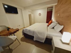 a bedroom with a bed and a table and a television at HOTEL CUSCO PERU in Cusco