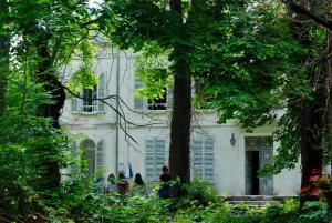 Una donna in piedi davanti a una casa bianca. di YXIE - Manoir des Arts a Villeblevin