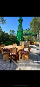 a wooden table and bench with a green umbrella at Etno selo Raj na Uvcu in Sjenica