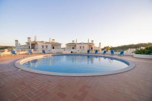 une grande piscine au milieu d'un patio dans l'établissement Budens 37, à Budens