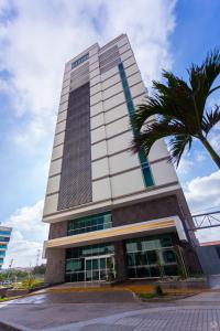 a tall building with a palm tree in front of it at Sky Collection Lifestyle Hotel & Suites Barranquilla in Barranquilla