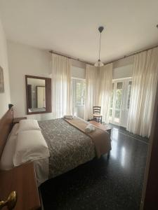 Schlafzimmer mit einem Bett, einem Spiegel und Fenstern in der Unterkunft Hotel La Pineta in Cogoleto