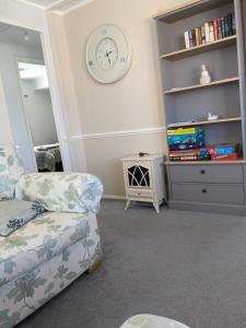 a living room with a couch and a clock on the wall at Colins holiday home in Hull