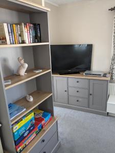 a living room with a tv and a book shelf at Colins holiday home in Hull
