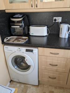 a kitchen with a washing machine and a microwave at Colins holiday home in Hull