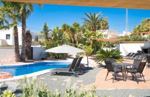 um pátio com cadeiras e um guarda-sol ao lado de uma piscina em Villa Sardonyx CostaBlancaDreams em Calpe
