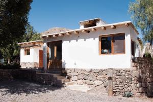 una pequeña casa blanca con una pared de piedra en Cabañas Tilcara Taki en Tilcara