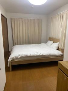 um quarto com uma cama grande e lençóis brancos em TOKYO池袋家族連れ4DKの子供連れ５星　 em Tóquio