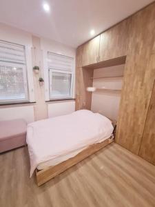 - une chambre avec un grand lit blanc et des placards en bois dans l'établissement Magnolia Pink Studio New and fully equipped, à Bruxelles