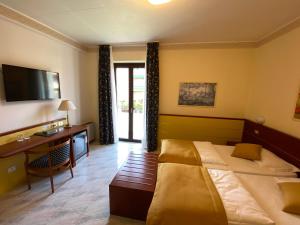 Habitación de hotel con 2 camas, escritorio y TV. en Hotel Villa Olivo Resort 3S, en Bardolino