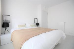 a white bedroom with a large bed with two lamps at Superbe appartement neuf à Liège Guillemins in Liège
