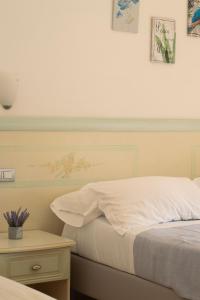 ein Schlafzimmer mit einem weißen Bett und einem Nachttisch mit Bildern an der Wand in der Unterkunft Le Case della Costa - Apartment Positano in Maiori