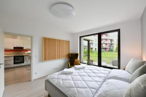 a white bedroom with a large bed and a kitchen at Golf Apartment 114 in Beroun