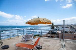un patio con una silla y una sombrilla y el océano en Nefeli Rooms, en Agia Marina de Nea Kydonia