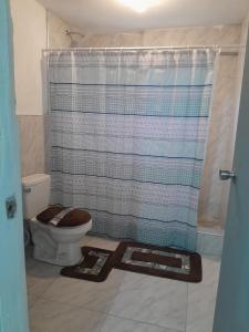 a bathroom with a toilet with a shower curtain at Cozy 2 bed in Ocho Rios in Ocho Rios