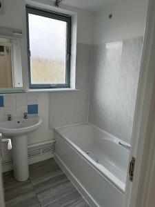 baño con bañera, lavabo y ventana en Newbury, en Londres