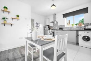 a white kitchen with a table and white chairs at New Luxury Apartment - Cradley Heath - 2MH - Parking - Netflix - Top Rated in Birmingham