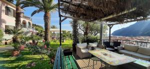 a patio with a table and couches and palm trees at Agriturismo Villa Bardi struttura con camere vista mare in Riva Trigoso