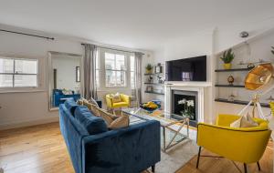 a living room with a blue couch and yellow chairs at Beautiful House in Knightsbridge in London