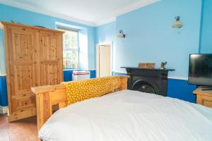 - une chambre avec un lit, une télévision et des murs bleus dans l'établissement Willsgrove House, à Athy