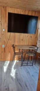 mesa con 2 sillas y TV en la pared en Noclegi u Ewusi 2, en Januszowice
