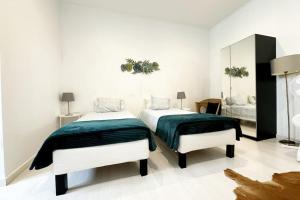 Habitación blanca con 2 camas y espejo. en Alcântara Studio 15, en Lisboa