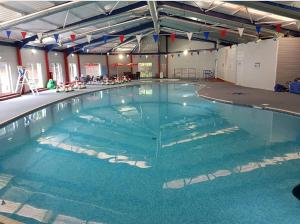 een groot zwembad met blauw water in een gebouw bij Hobbit - Holiday Lodge in Longridge