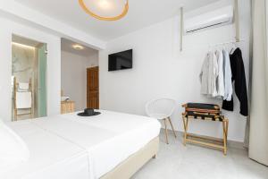- une chambre blanche avec un lit et une chaise dans l'établissement Golden Bird's, à Naxos Chora