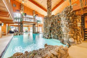 a large indoor swimming pool with a stone wall at Bloomfield Retreat with Indoor Pool and Tennis Court! in Bloomfield Hills