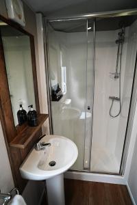 een badkamer met een douche en een witte wastafel bij Hobbit - Holiday Lodge in Longridge