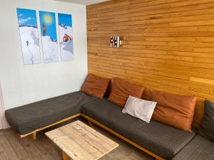 a couch in a room with a wooden wall at travelski home classic - Résidence Bellecôte in La Plagne