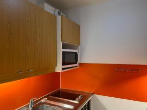 a kitchen with a sink and a microwave at travelski home classic - Résidence Bellecôte in La Plagne