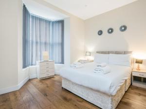 Ealing Queen of the Suburbs One Bedroom Apartment Pass the Keys في لندن: غرفة نوم بيضاء مع سرير كبير ونافذة