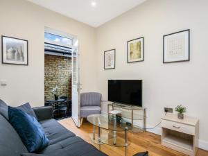 Ealing Queen of the Suburbs One Bedroom Apartment Pass the Keys في لندن: غرفة معيشة مع أريكة وتلفزيون