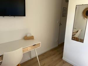 a room with a desk with a television and a mirror at Hôtel Paradis in Bormes-les-Mimosas