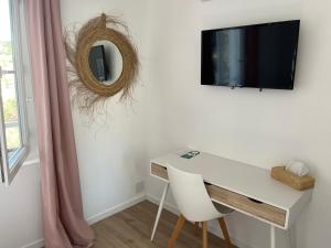 a white desk with a mirror and a tv on a wall at Hôtel Paradis in Bormes-les-Mimosas
