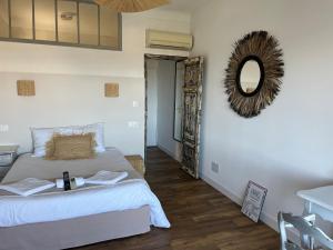 1 dormitorio con cama, espejo y mesa en Hôtel Paradis, en Bormes-les-Mimosas