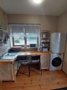 kuchnia z biurkiem z krzesłami i lodówką w obiekcie Gustiņi w mieście Baltezers