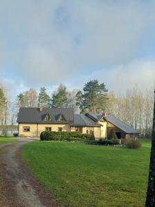 een groot wit huis met een zwart dak bij Gustiņi in Baltezers