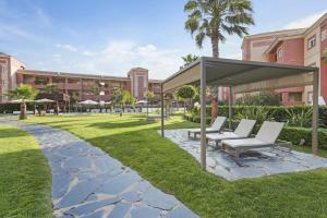 - un kiosque avec des chaises blanches dans un parc dans l'établissement AMA Residences Andalucia, à Islantilla