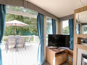 un salon avec une télévision et une terrasse dans l'établissement Dog Friendly 3 Bedroom Static Caravan In Fritton, à Belton