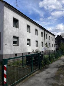 un edificio blanco con una valla delante en FlattyOne Ruhrgebiet - Schlafkomfort und Anbindung - neu renoviert en Bochum