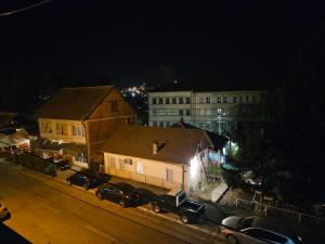 a city at night with cars parked in front of buildings at Apartman NINA in Kuršumlija