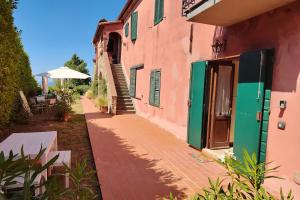 Un edificio rosa con persianas verdes y una acera. en Green View Apartment with pool, en Castiglioncello